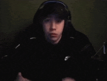 a young man wearing headphones and a hat is sitting in front of a microphone .