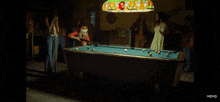 a group of people playing pool under a stained glass light