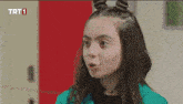 a girl is making a funny face in front of a trt 1 logo