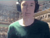a young man wearing headphones is standing in front of a shelf .