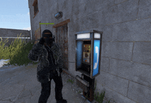 a man wearing a mask talks on a phone next to a pay phone