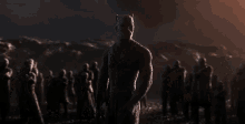 a man is standing in front of a crowd of people in a dark room holding a gun .