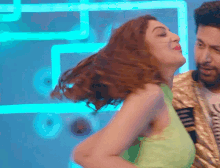 a woman in a green tank top is dancing with a man