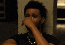 a man in a black shirt is crying and covering his face