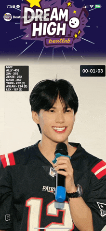 a young man in a patriots jersey holds a microphone