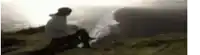 a blurry picture of a person sitting on top of a grass covered field .