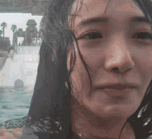 a close up of a woman 's face in the water with a water slide in the background