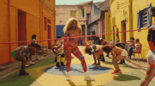 a woman in a colorful outfit is dancing in front of a crowd of people