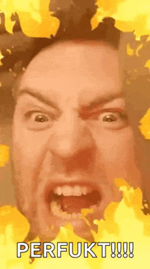 a man is making a funny face with his mouth open in front of a fire background .