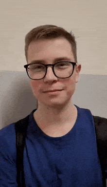 a man wearing glasses and a blue shirt is taking a selfie .