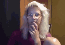 a blonde woman wearing glasses and headphones looks at the camera