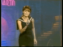 a woman singing in front of a martin sign