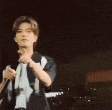 a young man is holding a microphone and giving a middle finger .