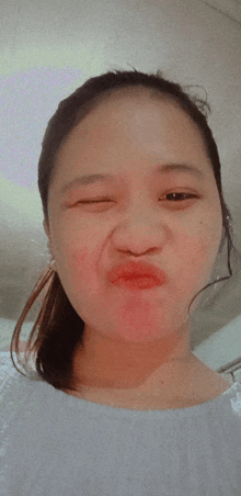 a girl with a ponytail making a funny face with her eyes closed