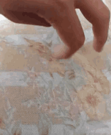 a close up of a person 's foot on a floral blanket on a bed .