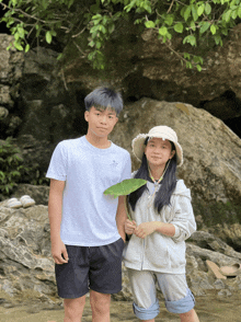 a boy and a girl are standing next to each other holding a leaf