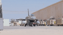 a fighter jet is parked in front of a warehouse