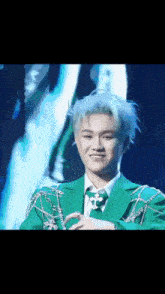 a man in a green suit and tie is smiling on a stage .