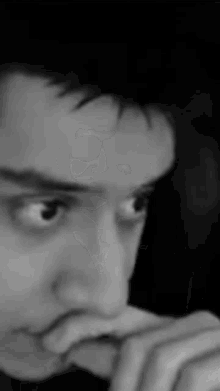 a close up of a man 's face with his hand on his mouth .