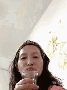 a woman wearing a green headband drinking from a glass