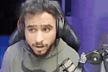 a man with a beard is wearing headphones and a moustache while sitting in front of a microphone .