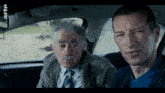 two men sitting in a car with the word arte on the bottom right