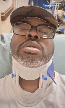 a man wearing glasses and a neck brace looks tired