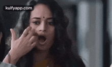 a woman is making a funny face with her mouth open and her hands on her face .