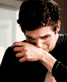 a man covering his mouth with his hand while looking down