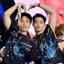 two men are making a heart shape with their hands .