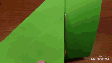 a person is cutting a piece of green paper with scissors and the words made in animatica are visible