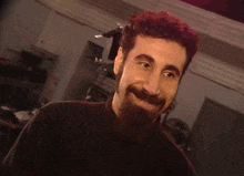 a man with a beard and a black shirt smiles for the camera