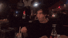 a man is sitting at a table with a straw in his mouth