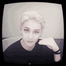 a young man with blonde hair is sitting in front of a tv
