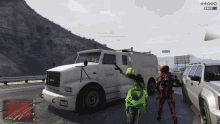 a person on a green motorcycle is standing in front of a white truck that says ' green valley ' on it