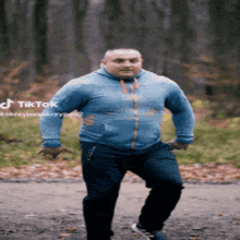 a man in a blue hoodie is walking down a road with a tiktok watermark