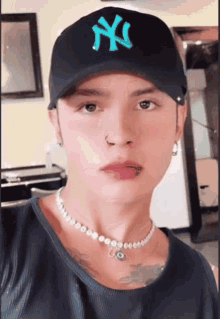 a man wearing a ny hat and a necklace