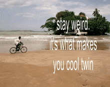 a man riding a bike on a beach with the words " stay weird it 's what makes you cool twin "