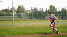 a man is running on a soccer field with a fence in the background .