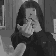a girl is taking a picture of herself in the mirror while giving the middle finger .