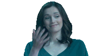 a woman in a blue shirt is smiling and talking on a cell phone