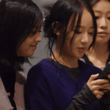 a woman in a blue sweater is holding a cell phone