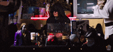 a man in a hood sits at a desk with a star wars book