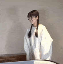 a girl with braids wearing a white sweater