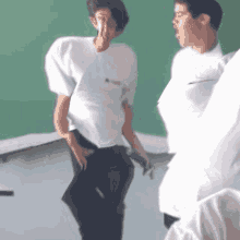 a man in a white shirt that says ' a ' on it is standing next to another man