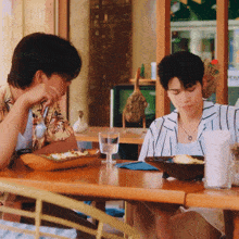 a man and a woman sit at a table with plates of food and a glass of water