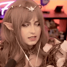 a woman in a fairy costume is talking into a microphone while wearing headphones and a headband .