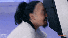 a man with a ponytail is looking at a computer screen that says prime on the bottom