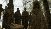 a group of people standing around a tree with ropes around their waists