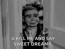 a black and white photo of a puppet in a suit and tie standing in a doorway .